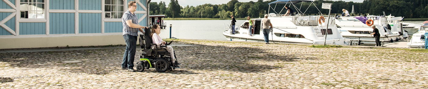 Elektrorollstuhl Layoutbild mit dem Elektrorollstuhl zum Bootsanleger an einem Fluß